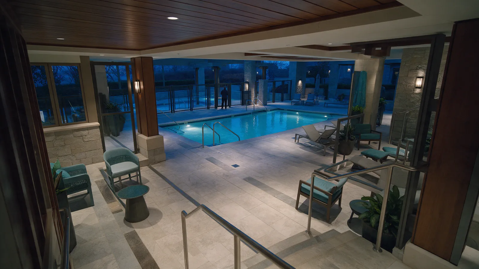 Illustrative after-hours hotel pool deck with a distant figure beyond an access gate.